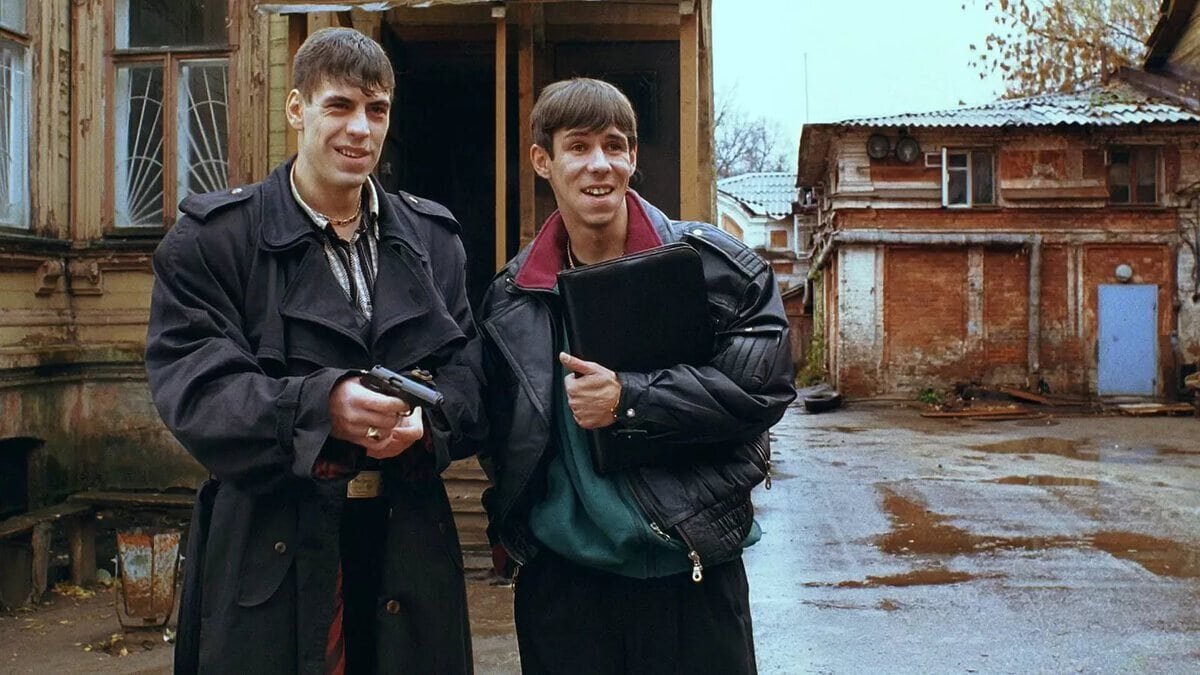 Криминальная комедия «Жмурки» известного российского режиссера Алексея Балабанова вышла в прокат в 2005 году. Название киноленты дает отсылку к старой одноименной игре, суть которой заключается в том, что человек с завязанными глазами должен поймать других игроков. В России 90-х старинная забава стала интерпретироваться иначе: победитель тот, кто сделает «жмурами» соперников, сам оставшись при этом в живых. В фильме рассказывается история Сергея и Саймона, двух мелких бандитов из провинциального городка, которые работают на серьезного криминального авторитета Сергея Михайловича. Провалив очередное задание, парни получают серьезное предупреждение от начальника. Сергей Михайлович предоставляет им возможность реабилитироваться и дает новое поручение. Однако незадачливые бандиты снова попадают в крупные неприятности