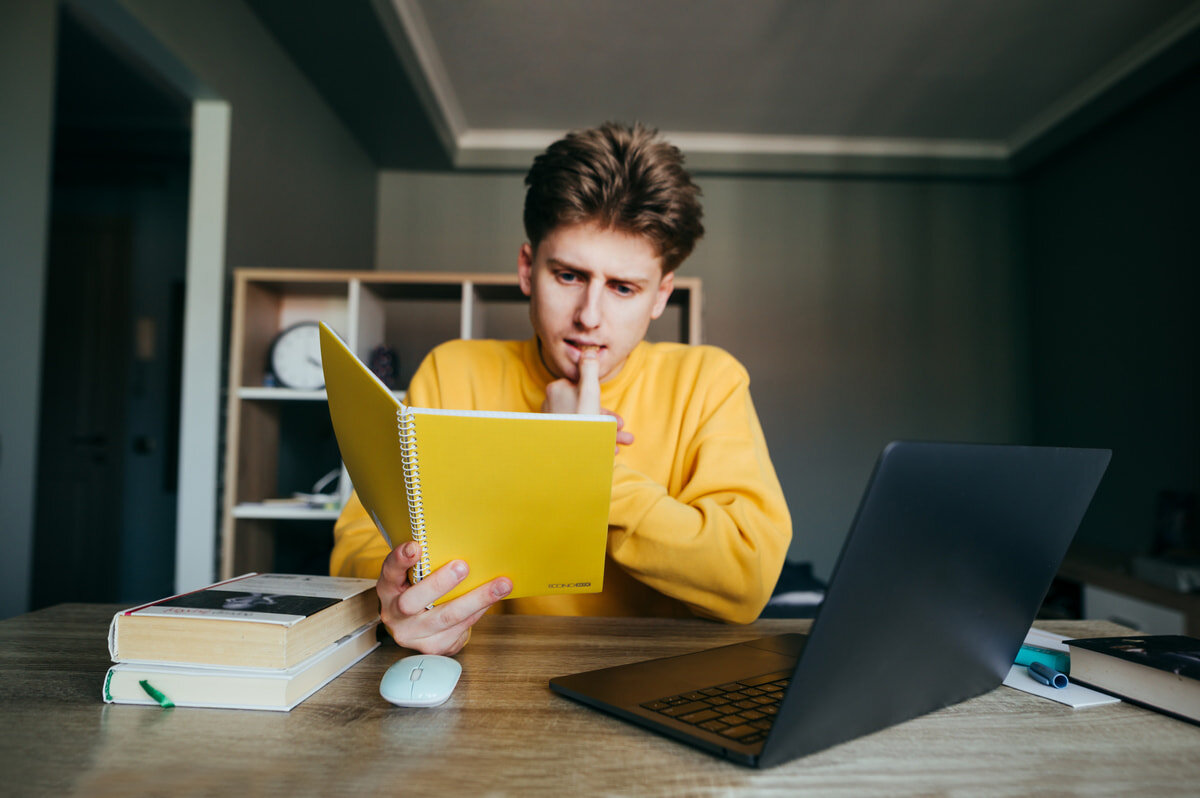 Thinking room. Умный студент. Фото человек выбирает что почитать в ноутбуке. Remote study. Консультация людей сидят за столом с книгой.