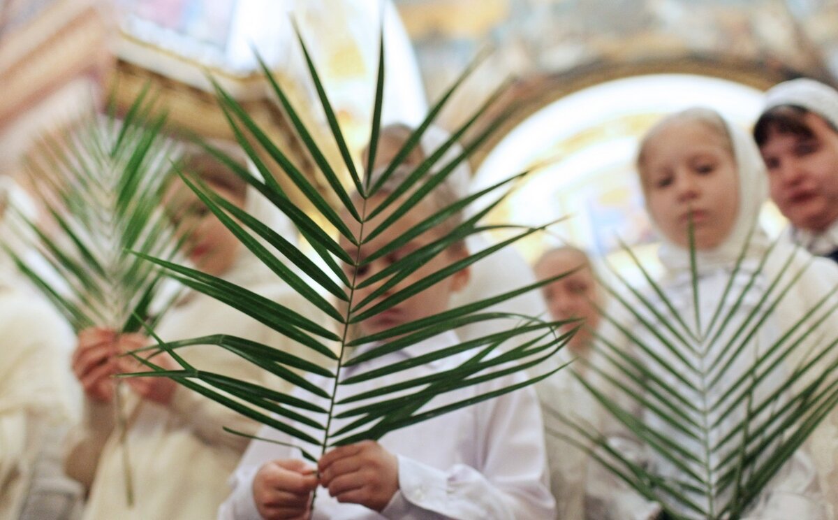 Дети на христианском празднике несут ветви пальмы