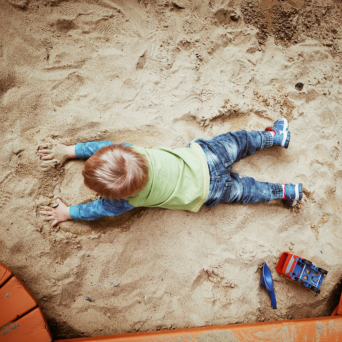 Мой младший сын в песочнике насыщается сенсорным опытом.