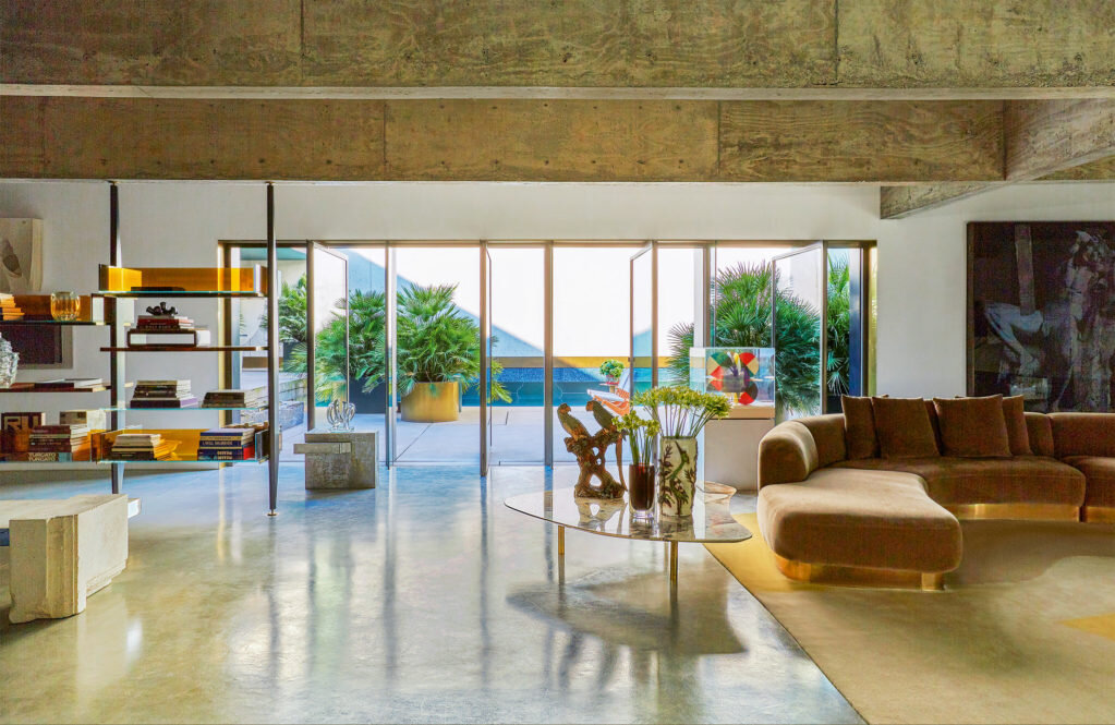 Окна в железной раме в гостиной открывают вид на террасу. Диван, журнальный столик и стеллаж — все придумал Де Котис.