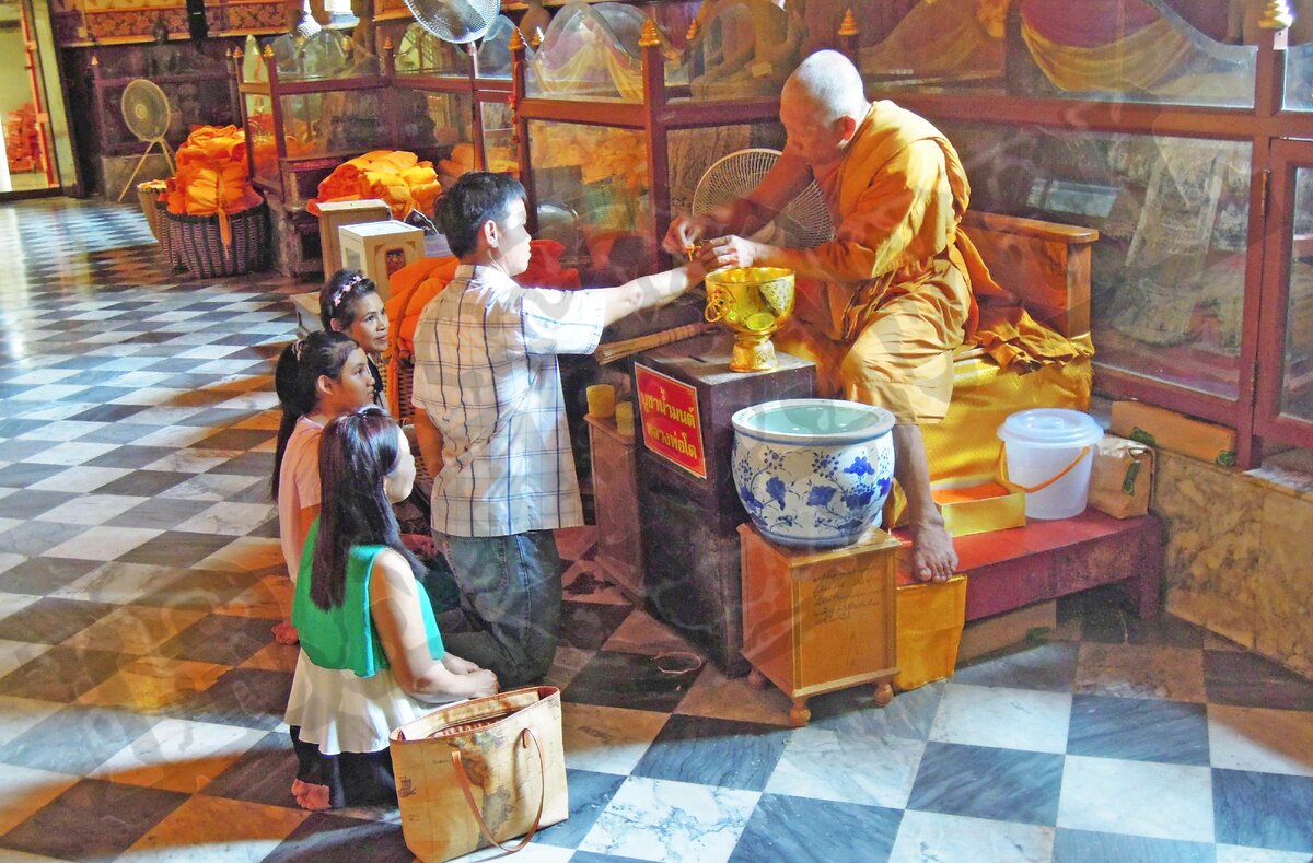 Повязывание защитной нити Сай Син в одном из храмов Таиланда. Справа чаша для пожервований (фото автора)