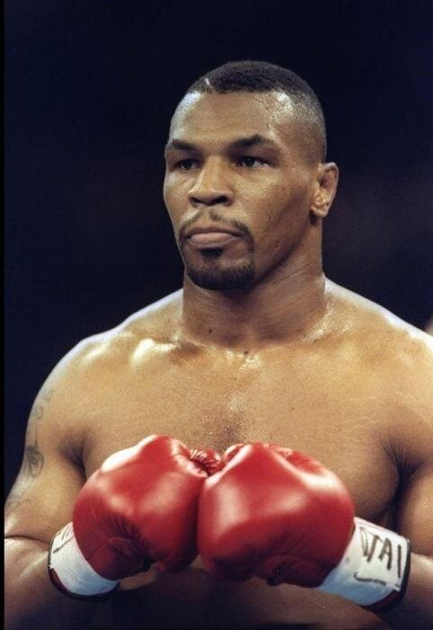 Правый кросс Майка Тайсона Сила удара: 700-1800 PSI
Один из лучших панчеров в истории мирового бокса, черный сплав животной агрессии, молниеносной скорости и разрушительной мощи Майк Тайсон был настоящим специалистом по нокаутам. На заре карьеры Тайсон устраивал настоящий геноцид на ринге — зачастую соперники принимали горизонтальное положение уже в первых двух раундах. Не зря обозреватель спортивного портала ESPN Грэм Хьюстон поставил Майка на первое место в рейтинге лучших нокаутеров всех времен. Это звание подтверждает и персональная статистика спортсмена — из 50 выигранных боев 44 Тайсон завершил нокаутом.
Самым страшным оружием Тайсона считался правый боковой — этот безупречный баланс между скоростью, работой корпуса и силой удара позволял ему укладывать соперников на пол пачками и обеспечивать работой не одного персонального дантиста. Не существует однозначного мнения о том, что касается абсолютной мощи удара Тайсона — силовая составляющая удара боксера колеблется в диапазоне от 700 до 1800 psi в зависимости от выбранного им удара. В любом случае при чистом попадании такой удар способен если не убить, то понизить показатель IQ противника на несколько десятков пунктов.