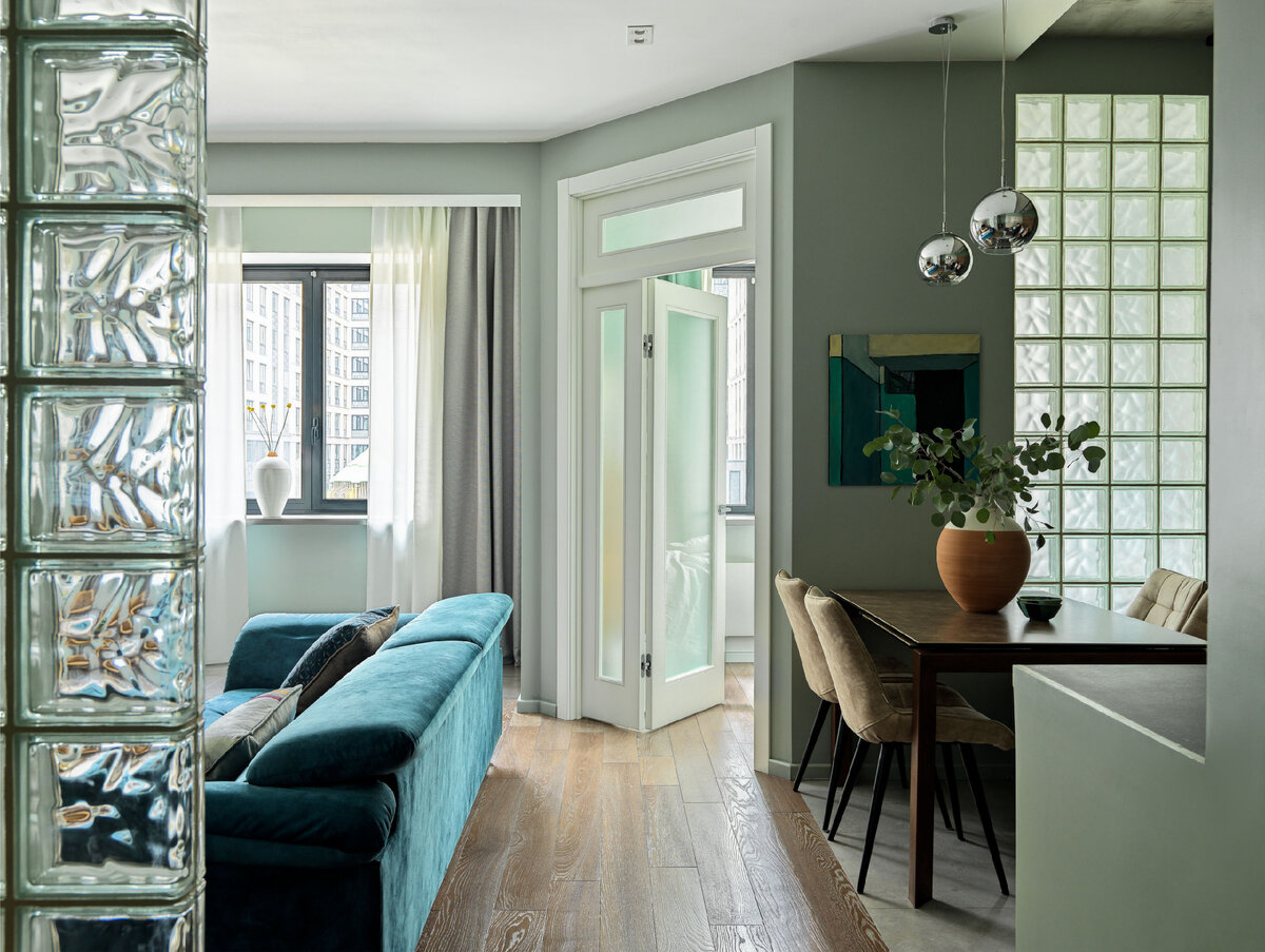 Нейтральный фон разбавили яркими предметами мебели в составе мягкой группы — бирюзовым диваном и жёлтым кожаным креслом.