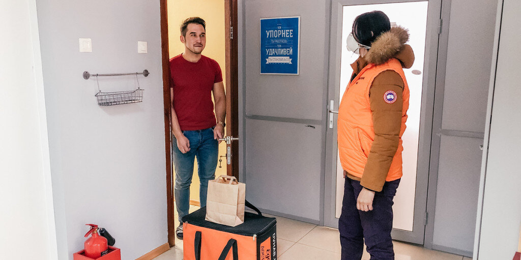 Курьер в маске доставляет заказ на дом