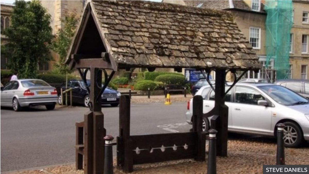 На фото: Деревянные колодки в городке Вудсток, Оксфордшир, - как ни странно, с пятью отверстиями для ног.