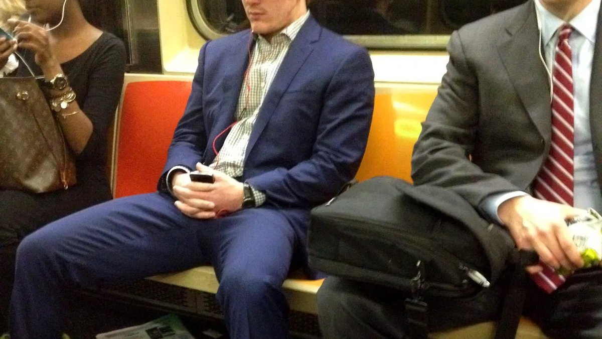 Мужчина сидит в метро. Мужчина сидит с широко расставленными ногами. Мужчина сидит в общественном транспорте. Ноги в общественном транспорте парней.