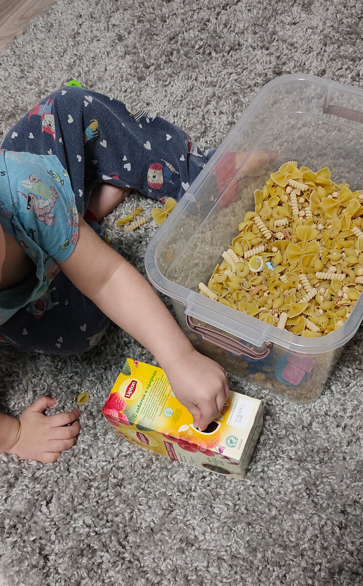 Вот наша сенсорная коробка с макаронами. Упаковка от чая тоже отлично подходит для развития мелкой моторики - в дырочки можно кидать макаронины.