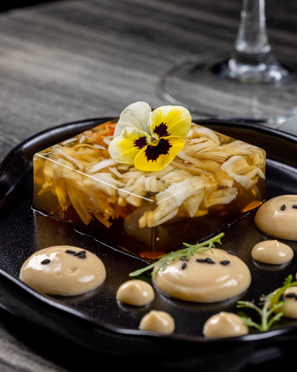 Ингредиенты: 
Мясо Камчатского краба 20гр
Бульон для заливного 60гр
Соус сливочный хрен 25гр

Бульон для заливного:
-рыбный бульон 60гр
-бульон даси 20гр 
-желатин листовой 4гр
-устричный соус по вкусу
-хондаши по вкусу
-соль, Сахар по вкусу 

Рыбный бульон:
-Обрезь и рыбные кости 
-Вода 
-лук репчатый
-Морковь 
-Сельдерей 

Бульон даси:
-бонито (стружка тунца) 20гр
-Комбу (морские водоросли сушеные) 25гр
-Вода 700гр

Соус сливочный хрен:
-Японский майонез 150гр
-устричный соус 5гр
-Соус свит Чили процеженный 10гр
-сливочный хрен 10гр

Приготовление: 
Для начала сварим рыбный бульон, для этого нам понадобиться обрезь и кости рыбы. Кладём их в кастрюлю и заливаем водой, в это время обжариваем на сухой сковороде одну луковицу, морковь, добавляем в нашу кастрюлю, для более яркого аромата, можно добавить сельдерей. Как только наш бульон закипел, снимаем пену, ставим на очень маленький огонь и томим еще 30 минут, затем процеживаем.
Затем бульон готовим бульон Даси, для него нам понадобиться 700грамм воды, 25 грамм Комбу(морские сушенные водоросли) 20грамм Бонито (стружка тунца).
В воду кладем Комбу, доводим до кипения, убираем Комбу, кладем бонито, снова доводим до кипения и процеживаем. 

Далее готовим бульон для нашего заливного. 
Берём 60 грамм рыбного бульона и 20 Даси, соединяем и доводим до вкуса устричным соусом, солью, соевым соусом и хондаши и добавляем 4 грамма замоченного желатина листового . 

Берём квадратную форму, кладем в нее очищенное мясо краба, заливаем нашим бульоном для заливного и отправляемся в холодильник на 3-4часа 

Тем временем готовим соус сливочный хрен 
Для него берём японский майонез 150грамм 
Добавляем в него 5грамм устричного соуса, 10грамм процеженного соуса свит Чили (сладкий Чили для курицы), сливочный хрен 10грамм, тщательно перемешиваем.

Собираем нашу закуску 
Берём тарелку, выкладываем наше заливное и рядом красиво добавляем соус 
Приятного аппетита и Счастливого Рождества! 