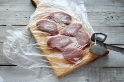 ШАГ 2:
Мясо нарезать поперек волокон, прикрыть пищевой пленкой и отбить молоточком.