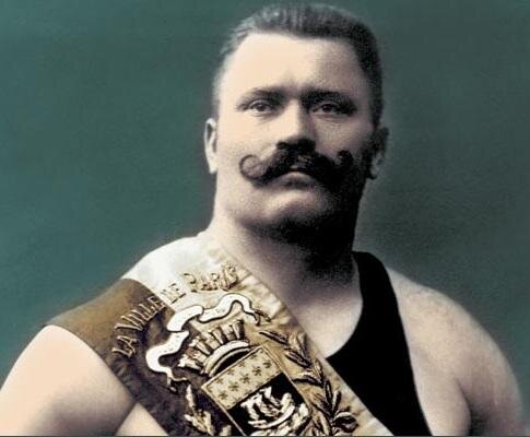 Пожалуй, нет в мире другого имени, которое бы так прочно ассоциировалось с огромной физической силой, как имя Ивана Поддубного. Этот легендарный тяжелоатлет родился на Полтавщине, в небольшом селе Красионивка в 1871 году. Отец и мать его были потомственными казаками и превыше всего ставили честь. Во всем селе отец Ивана – Максим Поддубный был самым сильным и удивлял односельчан своими возможностями. Сын пошел в отца и уже к 17 годам мог ворочать пятипудовые мешки с зерном и разгибать подковы. В двадцать лет Иван ушел из деревни на заработки в севастопольский порт, где устроился грузчиком. За невиданную силу и огромный рост все в порту с уважением называли его Иваном Великим. В 1895 Поддубный переезжает в Феодосию и начинает серьезные занятия гиревым спортом и борьбой. Уже в 98 году он одерживает первую победу в чемпионате цирка Труцци. В 1903 году Иван Поддубный вступает в петербургское атлетическое общество и в этом же году отправляется на чемпионат мира в Париж. Там он проигрывает Раулю ле Буше, который провел несколько приемов, запрещенных правилами. Однако уже в следующем году, Поддубный восстанавливает справедливость, одерживая победу над ле Буше в московском цирке Чинизелли. 