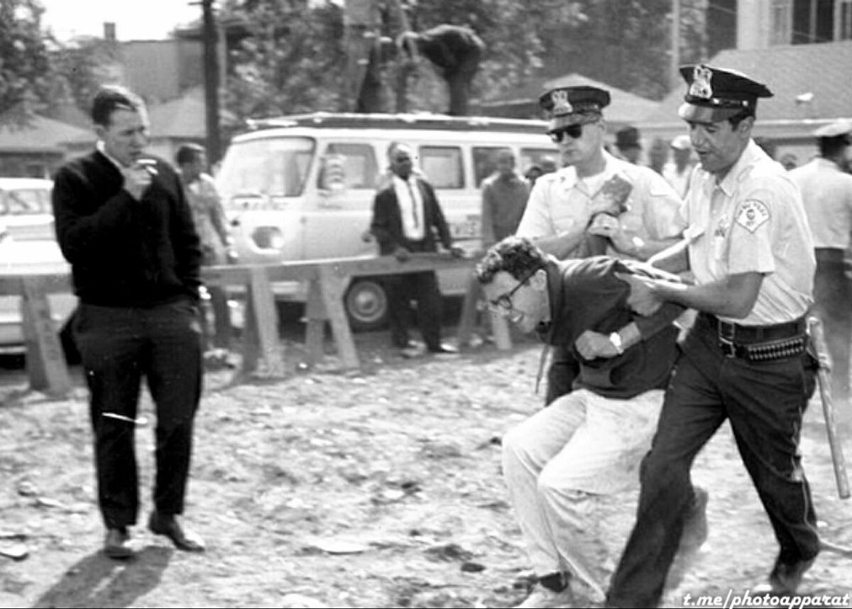 Будущего кандидата в президенты США Берни Сандерса в очередной раз задерживает полиция, Чикаго, 1963 год. 
На фото его, наверное, сотое задержание, а до этого полиция срывала листовки, им развешиваемые, высвобождала его из цепей, которыми он себя приковывал к протестующим неграм, ещё ложился на пути фургонов Уиллиса и множество раз сидел в "обезьяннике".