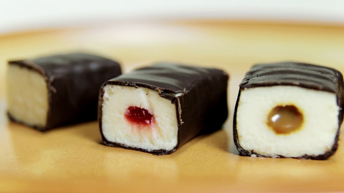 О пользе сырка Творожные сырки очень популярны в России и сейчас — россияне употребляют их до 45 000 тонн в год, — так сообщают специалисты из объединения Союзмолоко. Родители старались отвлечь детей от конфет и дать им полезный, как им казалось, продукт. По сути: глюкоза, содержащаяся в глазури и в твороге, должна придавать ребенку необходимую энергию, кальций в твороге — поддерживать крепость костей, полезные микроэлементы из какао или изюма — укреплять здоровье, а еще более полезные микроорганизмы из творога — способствовать работе желудочно-кишечного тракта. Возможно, так и было в СССР, но полезен ли сырок сейчас?
О вреде сырка
Во-первых, это творожное лакомство содержит огромное количество сахара — в одном единственном сырке может быть две чайные ложки этого вредного продукта. то есть до 40% от общей массы изделия. Во-вторых, в сырках много жира: как правило от 20% до 25% — то есть людям, которые испытывают проблемы с весом, покупать их не стоит. То же самое и с детьми, особенно с современными, которые ведут малоподвижный образ жизни. Диетолог Алла Погожева указывает, что калорийность одного сырка весом в 50 грамм составляет 135 кКал при жирности в 10,9%, и 207 кКал при жирности 27,7%. Употреблять такое лакомство можно не чаще одного — двух раз в неделю. Но самое главное — это низкое качество продуктов. По данным, которые приводит в статье «Глазированный десерт» газета «Санкт-Петербургские ведомости» (№ 186 (6295) от 08.10.2018) из семи протестированных системой контроля Роскачество глазированных сырков, в пяти образцах сам творог, который и считается самым полезным ингредиентом, оказался плохого качества. Согласно регламенту безопасности содержание дрожжей в нем не должно превышать 100 КОЕ/грамм, реальность же оказалась печальной — в некоторых сырках предельно допустимая концентрация дрожжей была превышена в 140 — в 150 раз, а в самых «безобидных» — в 5,5 и в 14 раз. Замечено, что иногда производители вместо творога используют так называемый «творожный продукт» — то есть некий продукт, произведенный из молока с добавлением кокосового или пальмового масла. Кроме этого, в лакомстве может встретиться консервант сорбиновая кислота, которую добавлять в творог недопустимо. Выяснилось, что жирность лакомства еще выше заявленной — то есть производители заманивают покупателей низкой калорийностью продукта, но это в некоторых случаях оказывается неправдой. Другие производители глазируют сырки так, что масса самой глазури достигает 41% — то есть о диетическом питании речь уже не идет. Хитрят производители и в производстве самой шоколадной глазури, в которой натуральные компоненты часто заменяют более дешевыми аналогами — используют кондитерский жир, которым заменяют масло какао, либо пальмовое или кокосовое масло.