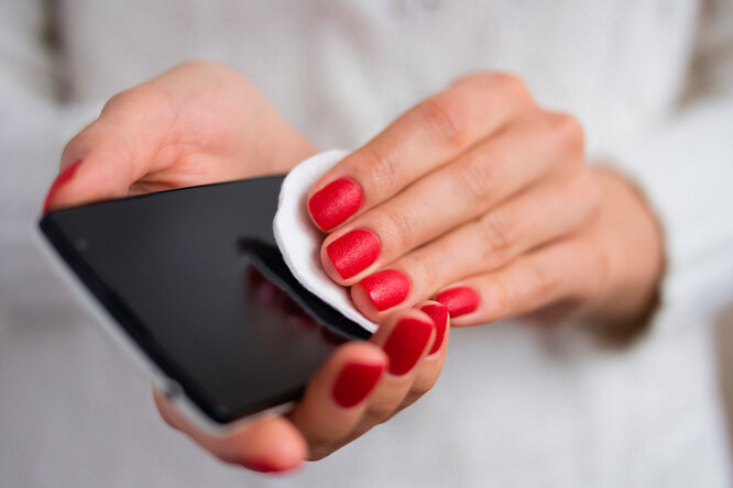 Мобильный телефон называют одним из самых загрязненных предметов в доме. И это не голословное утверждение – при исследовании смартфонов помимо обычной пыли и грязи ученые обнаруживают на корпусе следы паразитов, фекальных бактерий и даже потенциально опасных для жизни микробов. Весомая причина почистить телефон прямо сейчас – а мы расскажем, как правильно это сделать. Вопреки распространенному мнению средства для мытья окон и влажные салфетки для чистки смартфонов использовать нельзя. В состав бытовой химии часто входят довольно агрессивные вещества, способные испортить жидкокристаллический дисплей, а при проникновении внутрь – вызвать поломку всего устройства.
Также нельзя продувать смартфон феном (поверьте, так делают многие!), обрабатывать нашатырным спиртом, перекисью водорода, растворителями, хлоркой и абразивами, включая пищевую соду.
Для чистки и дезинфекции смартфона вам понадобятся:
•	дистиллированная вода;
•	70%-ный изопропиловый спирт;
•	пульверизатор;
•	салфетка из микрофибры для оптики или любая безворсовая ткань;
•	ватные палочки;
•	зубочистки.
При чистке телефона постарайтесь его сильно не мочить. Большинство производителей наносят на корпус и экран смартфона специальное гидрофильное покрытие, которое защищает устройство от кожного сала и других загрязнений. Сильное трение и излишняя влага могут его разрушить.
Как почистить смартфон
1.	Отсоедините от телефона аксессуары и выключите устройство.
2.	Снимите защитный чехол – его вы почистите отдельно.
3.	Налейте в небольшой пульверизатор дистиллированную воду и 70%-ный изопропиловый спирт в пропорции 1:1. Важно использовать именно дистиллат, так как обычная проточная вода может содержать микроскопические частицы минералов, которые могут поцарапать экран телефона.
4.	Нанесите раствор из пульверизатора на салфетку из микрофибры – так, чтобы она была едва влажной. Разбрызгивать жидкость сразу на телефон НЕЛЬЗЯ!
5.	Протрите салфеткой все части устройства с обеих сторон.
6.	Чтобы почистить такие детали как объектив фотокамеры, входные порты для аксессуаров или кнопки, используйте ватные палочки. Крошки и другие загрязнения, застрявшие в корпусе, удалите деревянной зубочисткой.
7.	Сушите телефон на воздухе не менее 15 минут.
