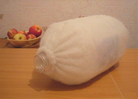 Необходима 5-литровая бутылка.  Бутыль нужно обернуть слоем синтепона, стянув края ниткой на горлышке и на дне. 