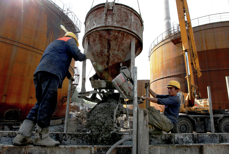 Рабочие выгружают раствор бетона во время строительства емкостей для мазутного топлива. Фото: Виталий Аньков / РИА Новости