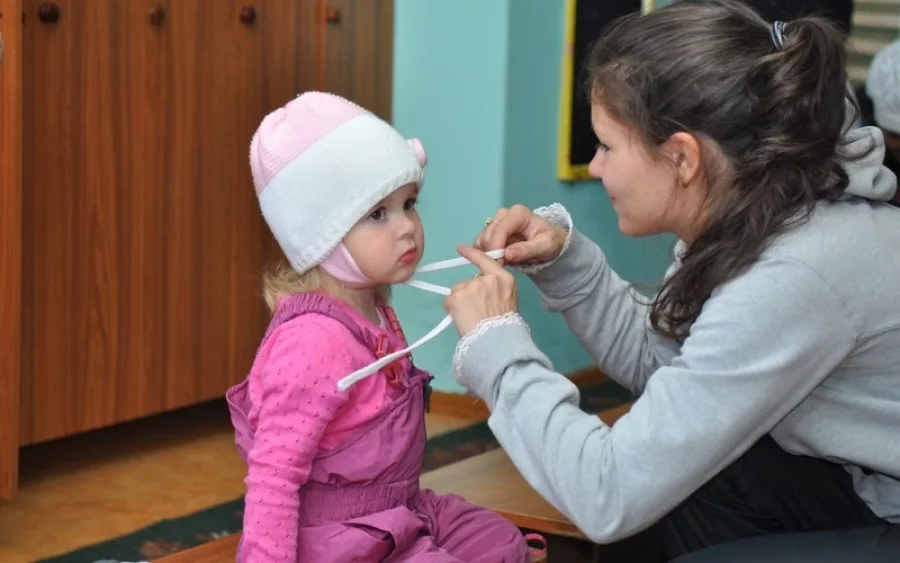 Детская одел. Мама одевает ребенка в детском саду. Дети одеваются на прогулку в детском саду. Одеть ребенка в садик. Одевание ребенка.