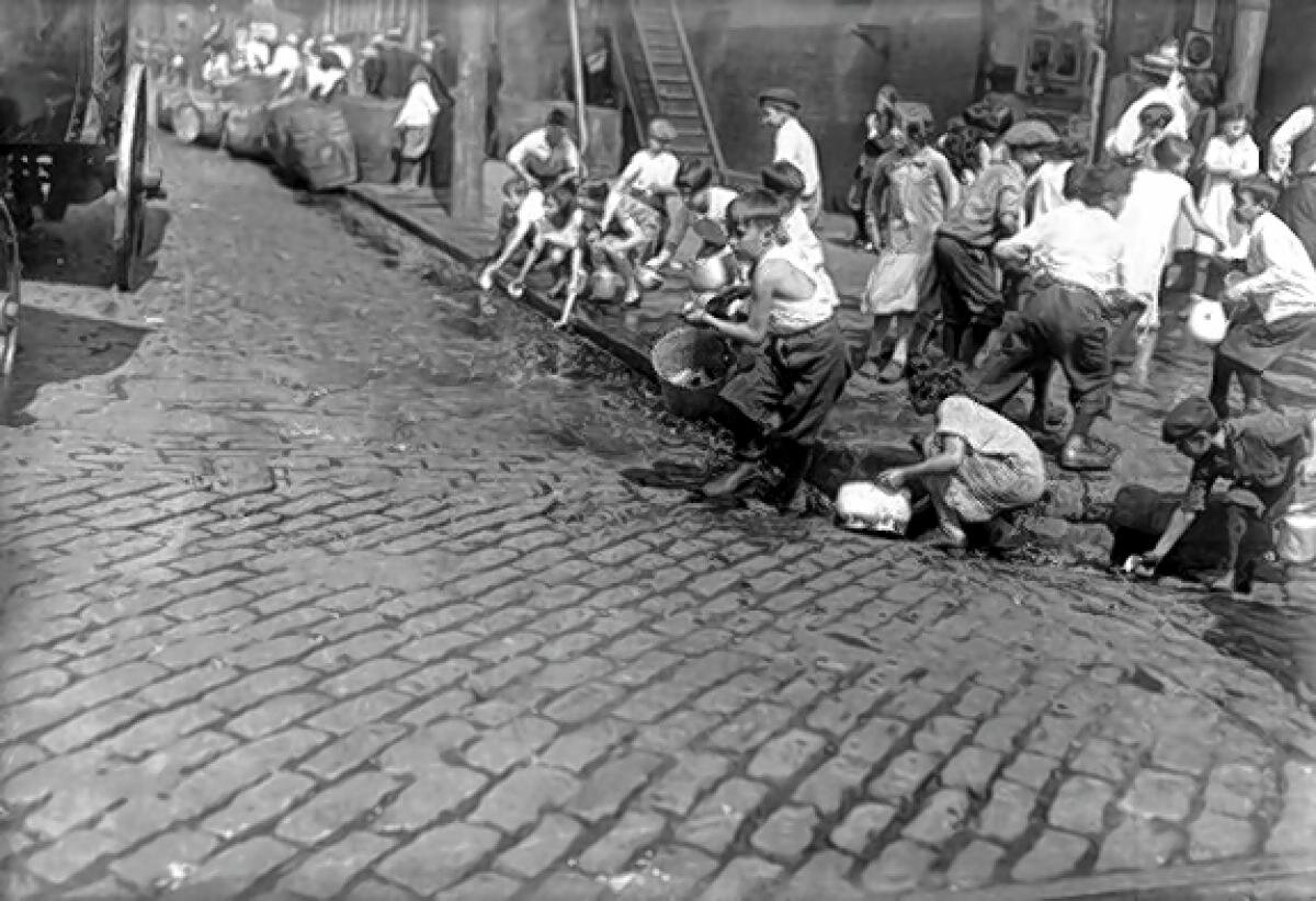 Дети собирают текущее по улице вино, которое было вылито агентами Bureau of Prohibition.