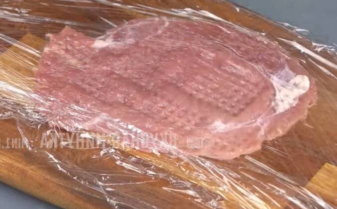 1. Нарезаем вырезку на отбивные. Накрываем пищевой пленкой досточку, выкладываем ломтик свинины, накрываем сверху вторым листом пищевой пленки, чтобы не было брызг. Отбиваем мясо молотком для отбивных. Солим, перчим по вкусу.