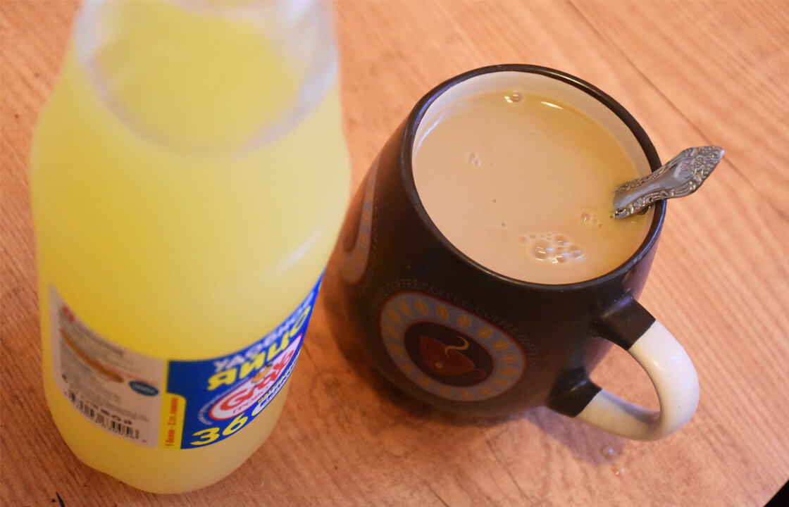 Пастеризованный яичный белок в бутылке и чашка кофе с молоком