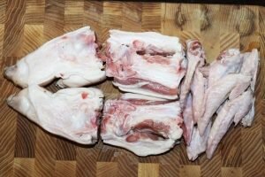 Главный элемент Тонкоцу Рамен – это густой свиной бульон. Вот с него и начнем. Кстати, бульон прекрасно хранится в замороженном виде, так что не переживайте – остатки бульонной основы не пропадут, просто заморозьте ее.
Для начала нужно подготовить свиную голяшку (славяне из них готовят чудесный холодец, да что уж там - и китайцы делают похожее блюдо).
Голяшку помыть, почистить и разрубить на 2-3 части, затем отрубы разрубить пополам вдоль.
