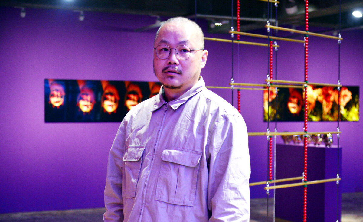 Художник Янгачи позирует перед своими работами в Barakat Contemporary (Пак Хён Ку / The Korea Herald)