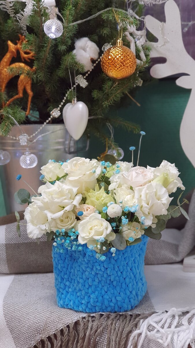 На фото: композиция в синем вязаном кашпо у елки.