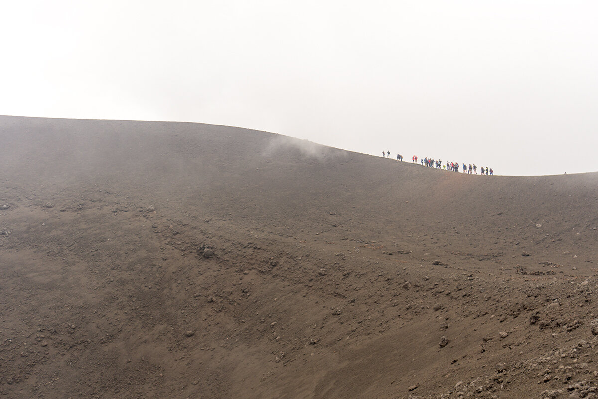 Люди идут вдоль кратера