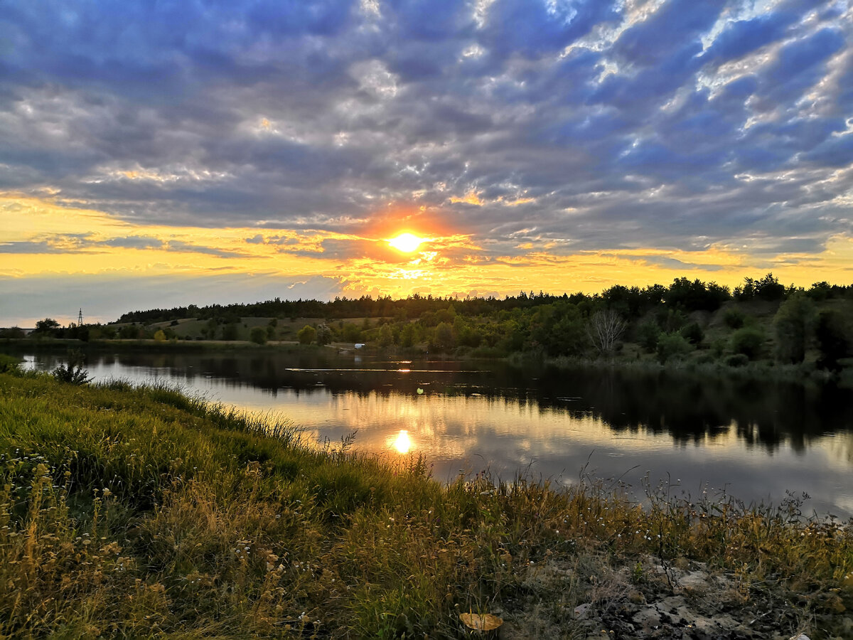    Закат над рекой, кажется что тучи полностью хотят поглотить солнце, но все равно удалось полюбоваться роскошным ярким заходом солнца. Еще немного и оно скроется за лесом, чтобы завтра подарить нам новый день