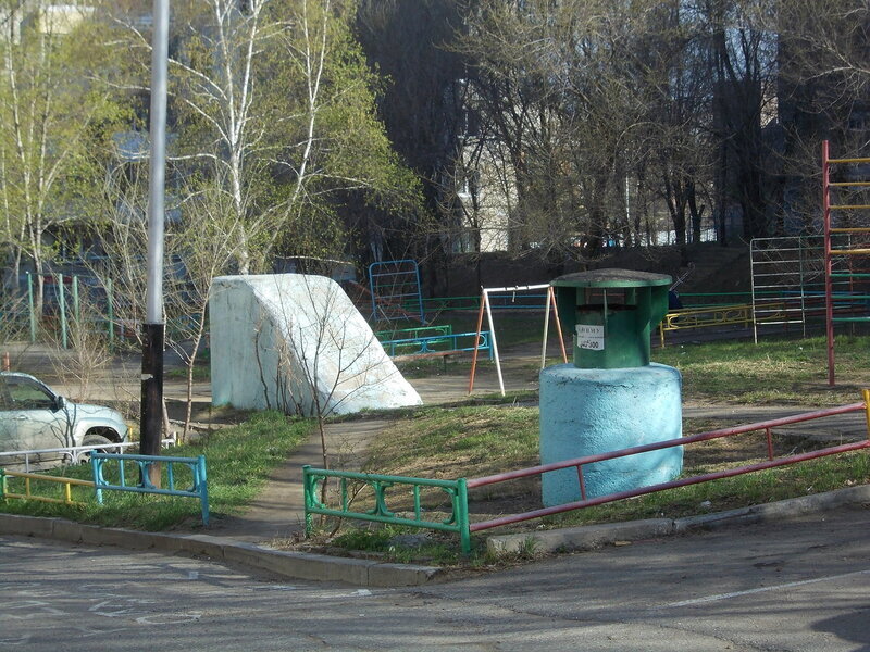 Прямо на детской площадке во дворе многоквартирного жилого дома можно увидеть железобетонный наклонный вход и вентиляционную шахту убежища встроенного типа, расположенного под самим домом. Именно туда мы и спустимся в этот раз.