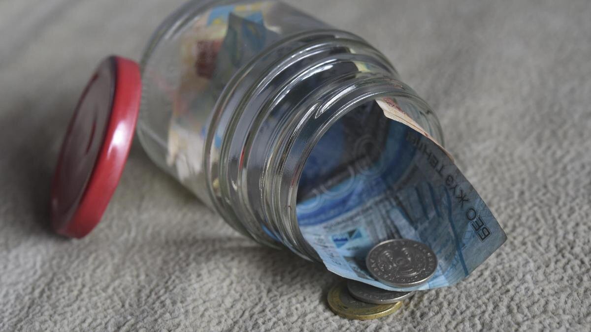    Купюры и монеты тенге лежат в стеклянной банке:NUR.KZ/Владимир Третьяков