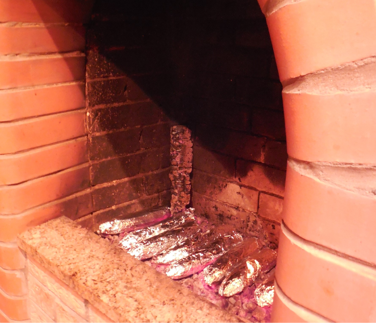 Кукуруза, завёрнутая в фольгу, печётся на горячих углах