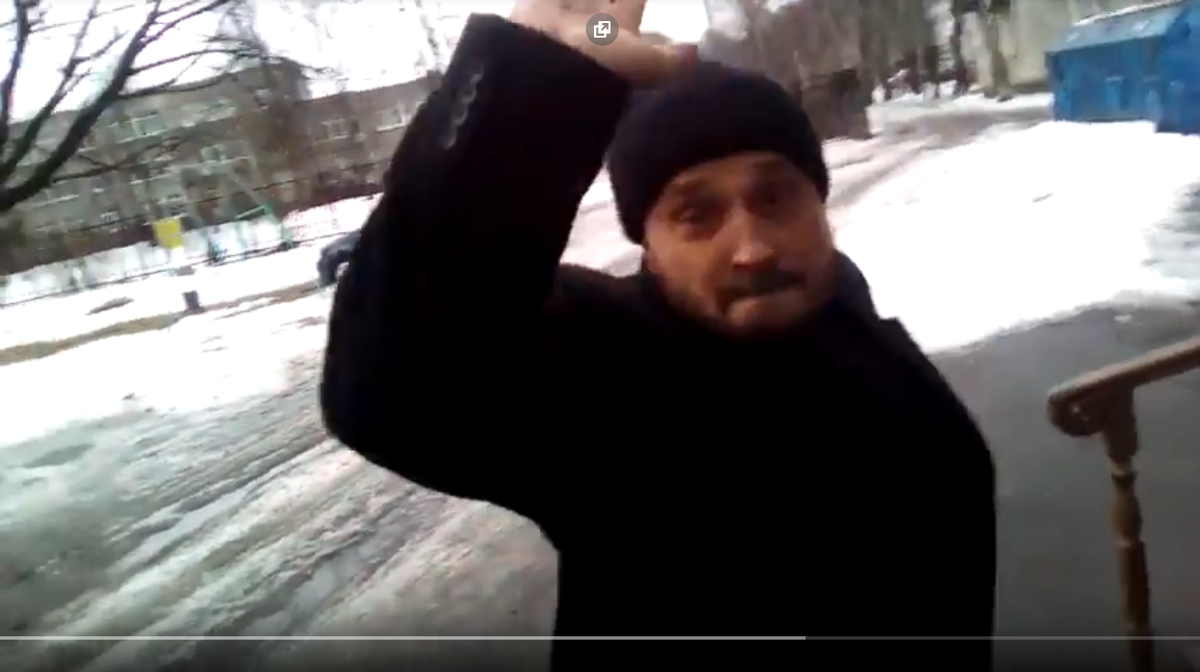 Кадр любительской видеосъёмки, на котором священник Максим Радаев замахивается на прихожанку.