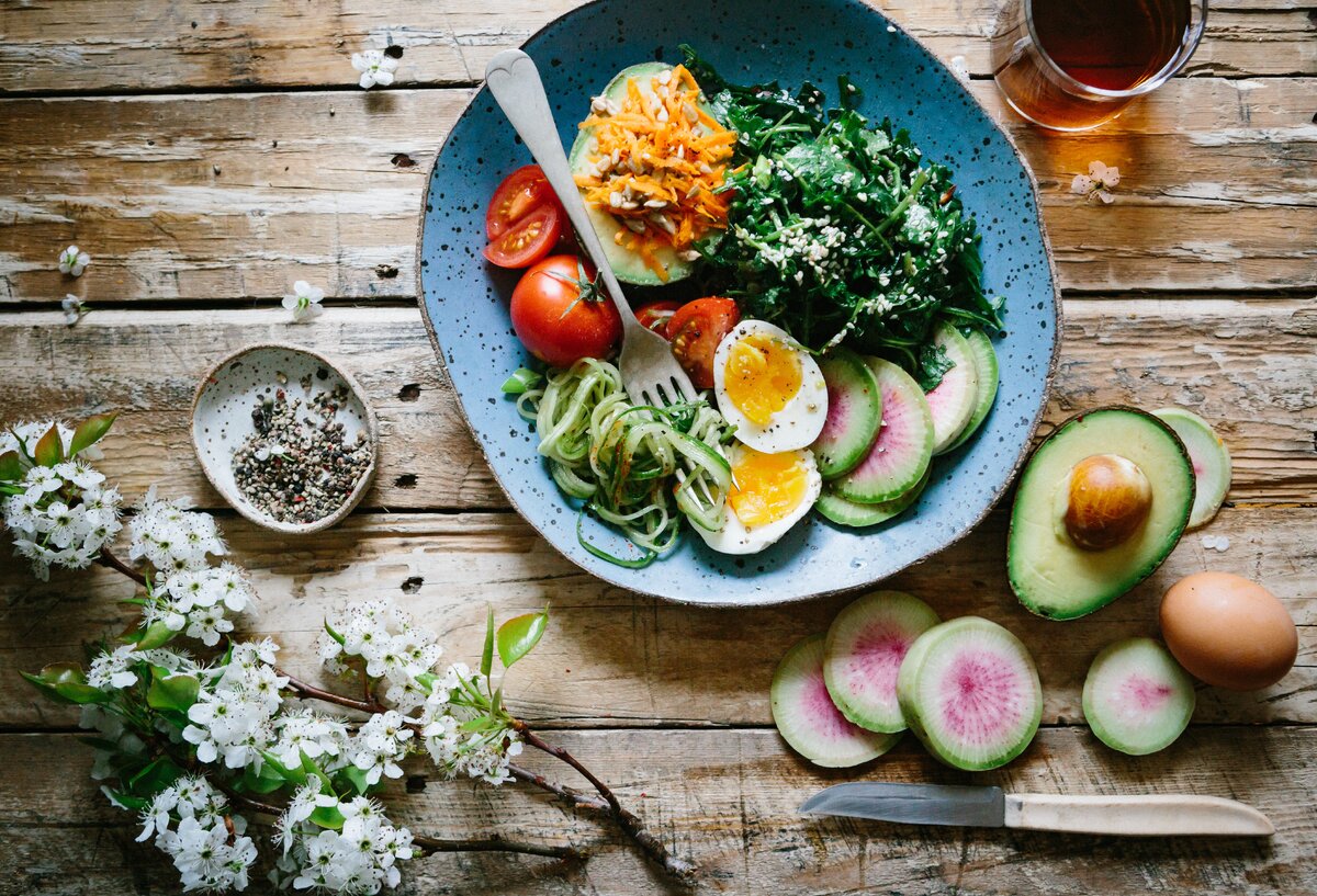 poached egg with vegetables and tomatoes on blue plate by Brooke Lark