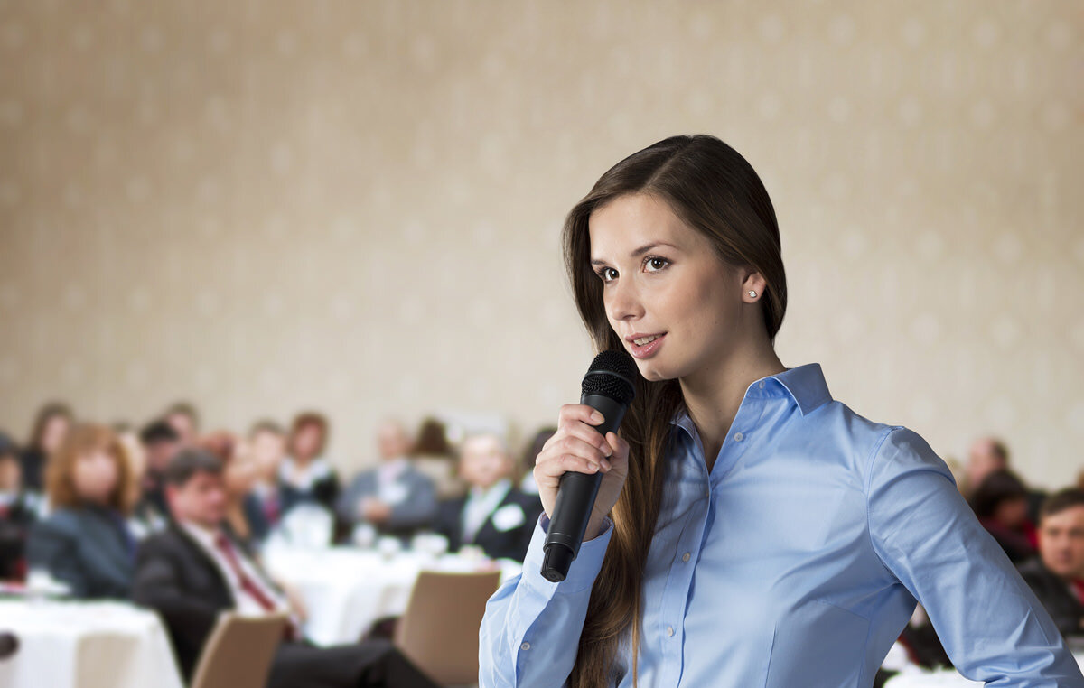Публичные выступления тренинг. Девушка выступает на конференции. Девушка оратор. Девушка выступает перед аудиторией. Женщина спикер.