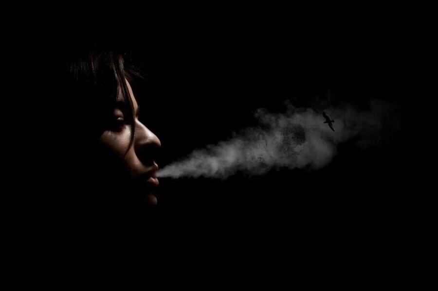 Струйки дыма тянулись навстречу брызгам. Дым изо рта. Девушка с дымом изо рта. Черный дым изо рта. Девушка выпускает дым.