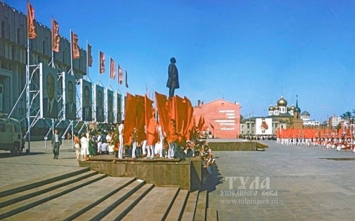 Празднование 40-летия Победы на пл. Ленина. Дом еще цел. Более того, он являлся частью архитектурного ансамбля площади, украшенный цитатой В. Ленина. Парадам явно не мешал. Автор фото Владимир Белтов 