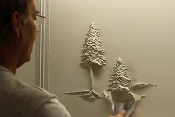 Берни Митчелл лепит барельеф из штукатурки.