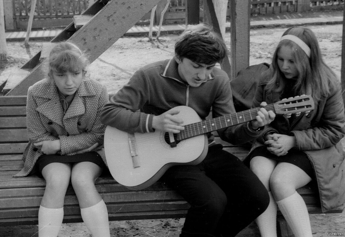 Парень играет на гитаре для двух старшеклассниц в мини-платьях