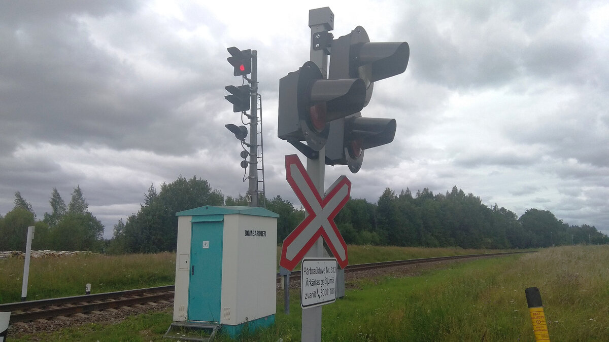 Входной сигнал станции и переездная сигнализация. Небольшая железнодорожная галерея с хмурым небом.