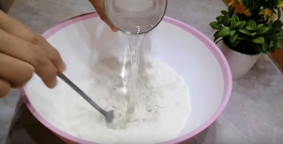В муку вылить воду с солью. Замесить мягкое тесто.