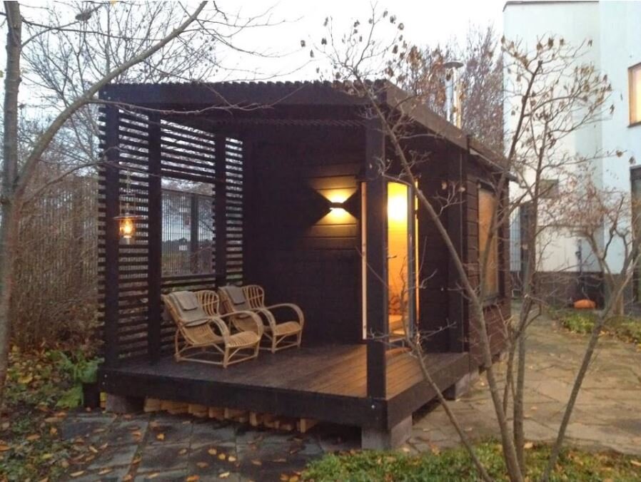 Баня в стиле барнхаус с крытой террасой. Большое окно в парилке — дань стилю. Хотя это весьма спорное решение. Но хозяевам нравится 🙂