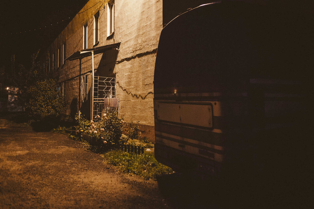 Здание общежития для водителей. Перед домом — стоянка. Там припаркованы рабочие машины «уберовцев» и два автобуса. Перед выездом на смену мужчины проверяют на этой стоянке свои автомобили, переговариваются. Фото: Александр Васюкович, Имена