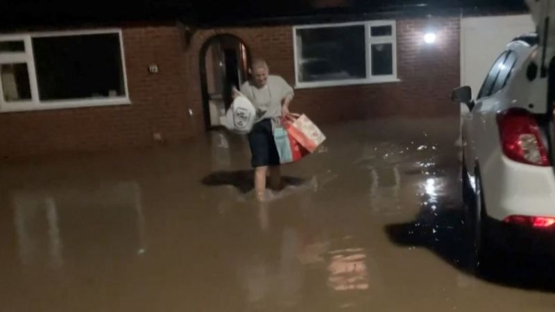 Женщина покидает затопленный дом. Уэльс. Фото ВВС.