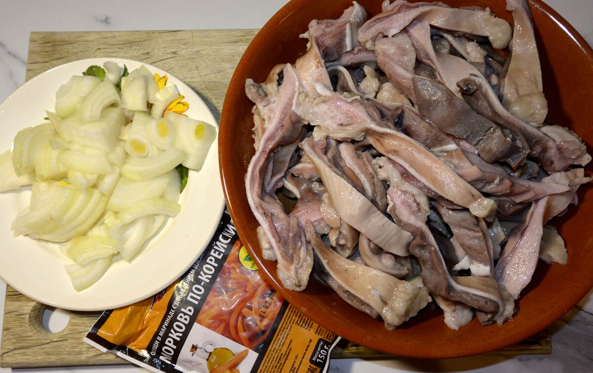 Свиной желудок отвариваем в подсоленной воде (соли смело кладем столовую ложку) около 1 часа, затем охлаждаем и нарезаем на полоски. Далее, нарезаем лук,  достаем покупную морковь по-корейски или приготовленную самостоятельно. 