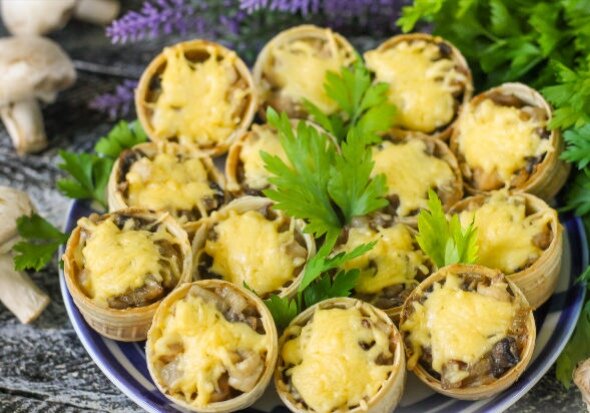 Очень сочная и аппетитная закуска - тарталетки с курицей, грибами и сыром. Особенно популярна эта закуска на праздничных столах - вмиг расходится с тарелок.