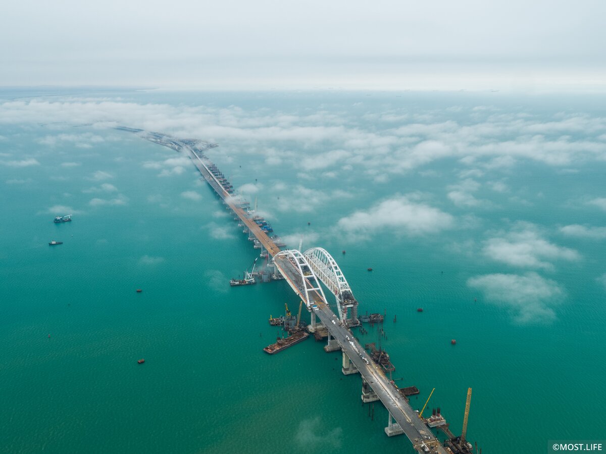 Как будут строить мост через Керченский пролив уже ясно. Теперь следует ответить на вопрос, какова длина строящегося моста в готовом виде. Здесь лучше привести следующие характеристики конструкции: 
Длина моста через Керченский пролив составит 19 км.
Для ускорения строительства было принято решение о строительстве с 8 точек одновременно.
Длины морских участков от косы Тузлы до острова и от острова Тузла до Керчи составит 7 и 6,1 км, соответственно. Мост частично проходит на острове, протяженность которого составит 6,5 км.
Для строительства будут задействовано около 600 опор, которые погрузятся вертикально или под наклоном.
Более 5,5 тысяч свай разных размеров требуется для строительства.