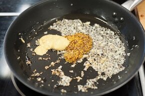Шаг 1На сковороде, где было мясо, приготовленные на разогретом жире нарежьте  мелко луковиц, добавить измельченный чеснок моменты все гори добавить обе горчицы, залейте 300 мл теплой воды.