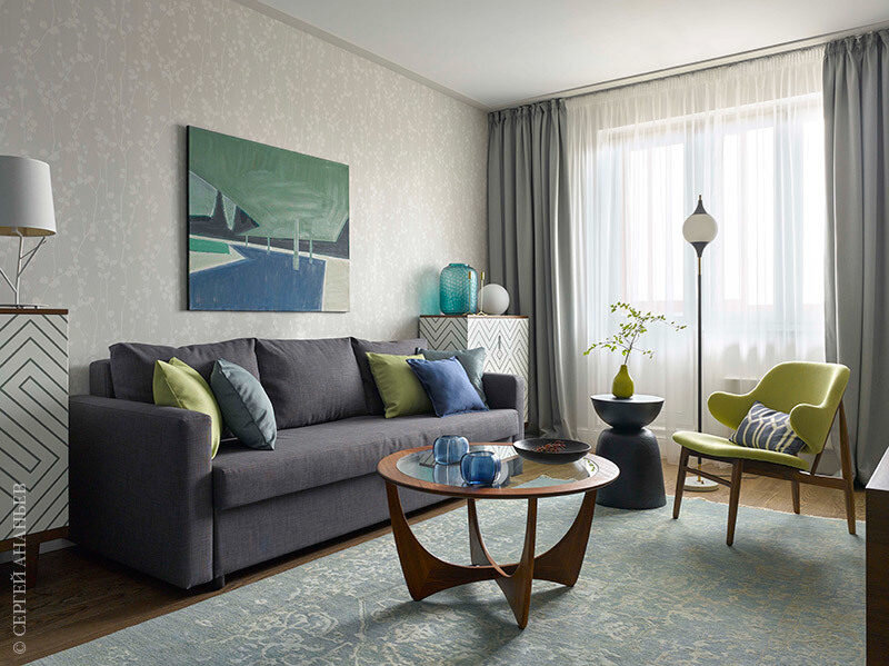 Журнальный стол — винтаж, Англия, 60-е годы. Комоды, The Idea. Светильники на комодах Faro, Artemide. Напольный светильник, Stilnovo, винтаж, магазин Lamps of 50–60–70-s. Ковер ручной работы, салон Lekover. Бирюзовая ваза на комоде, подсвечники на журнальном столе Guax, Predmety. Картина Светланы Шебаршиной “Полуденное солнце 1”, галерея Art Brut.