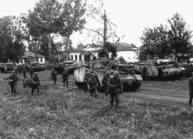 Пехота 20-й немецкой танковой дивизии перед танком Pz. IV, на заднем плане PZ. III, в том числе специализированный танк артнаблюдения. https://waralbum.ru/photocache/39/36/01/393601-files/393601-main.jpg